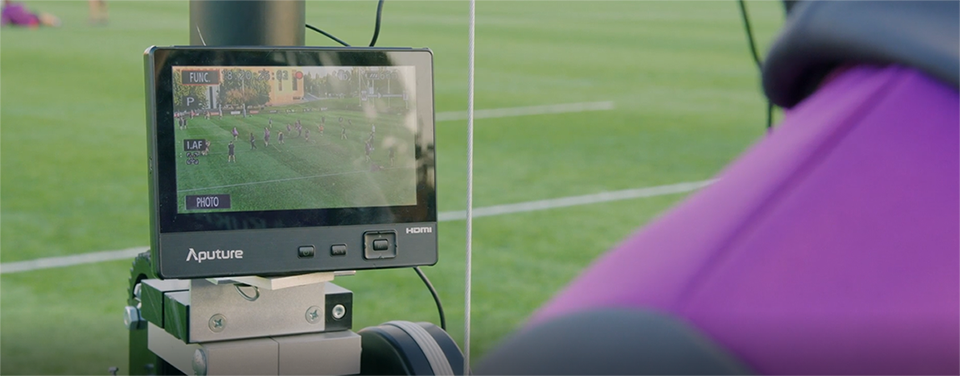 a person viewing a live match on a screen at the side of the pitch